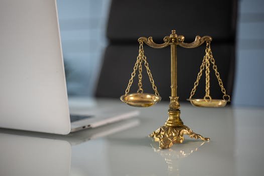 pexels-photo-6077797-6077797 Golden justice scales on a desk beside a laptop, symbolizing law and balance.