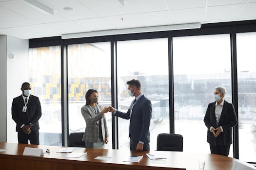 pexels-photo-6950037-6950037 Diverse professionals in formal attire fist bumping at a business meeting in a conference room.
